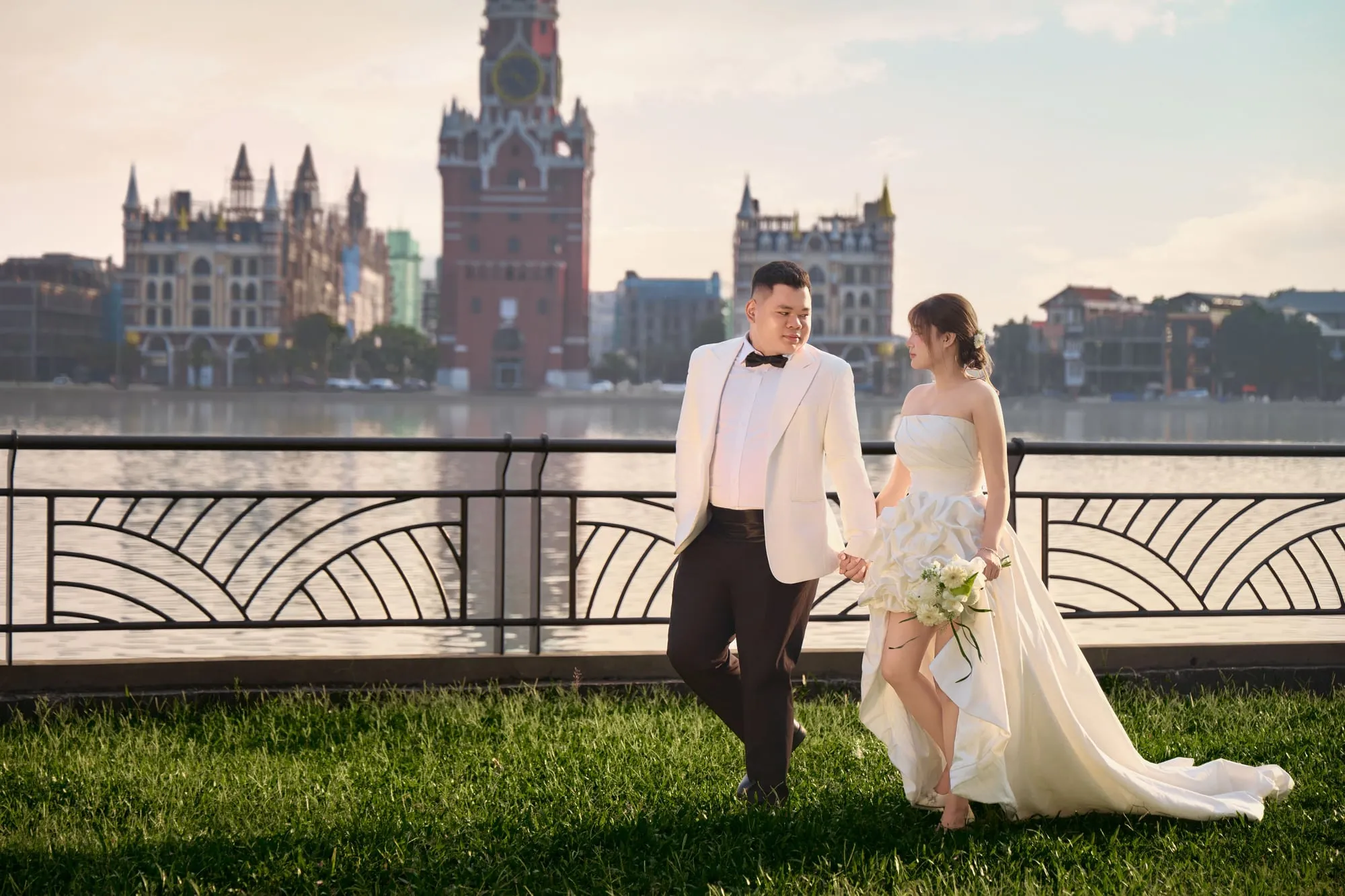 Hai người dạo bước bên hồ, phía sau là lâu đài